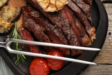 Photo of Delicious grilled beef with tomatoes and spices on wooden table, top view