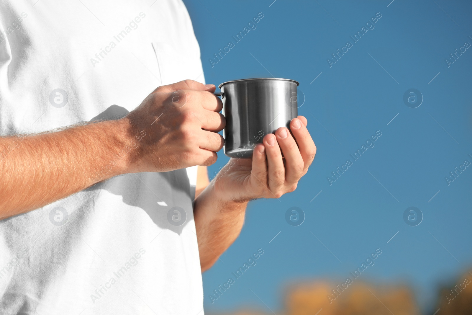 Photo of Male camper with metal mug outdoors, closeup. Space for text