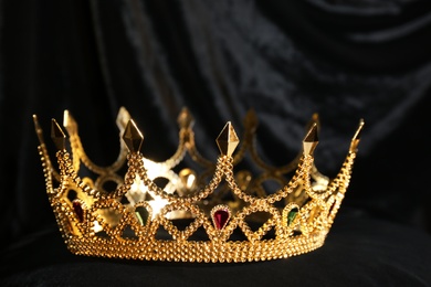 Photo of Beautiful golden crown on black fabric. Fantasy item