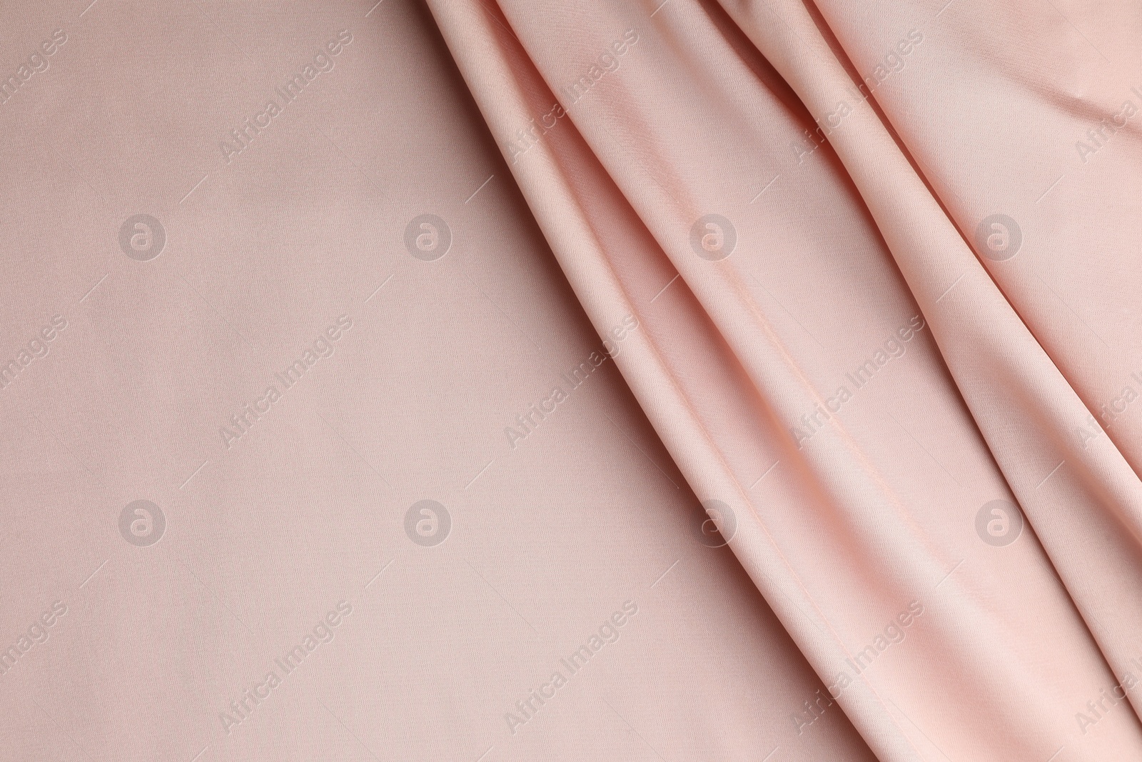 Photo of Crumpled pink silk fabric as background, top view. Space for text