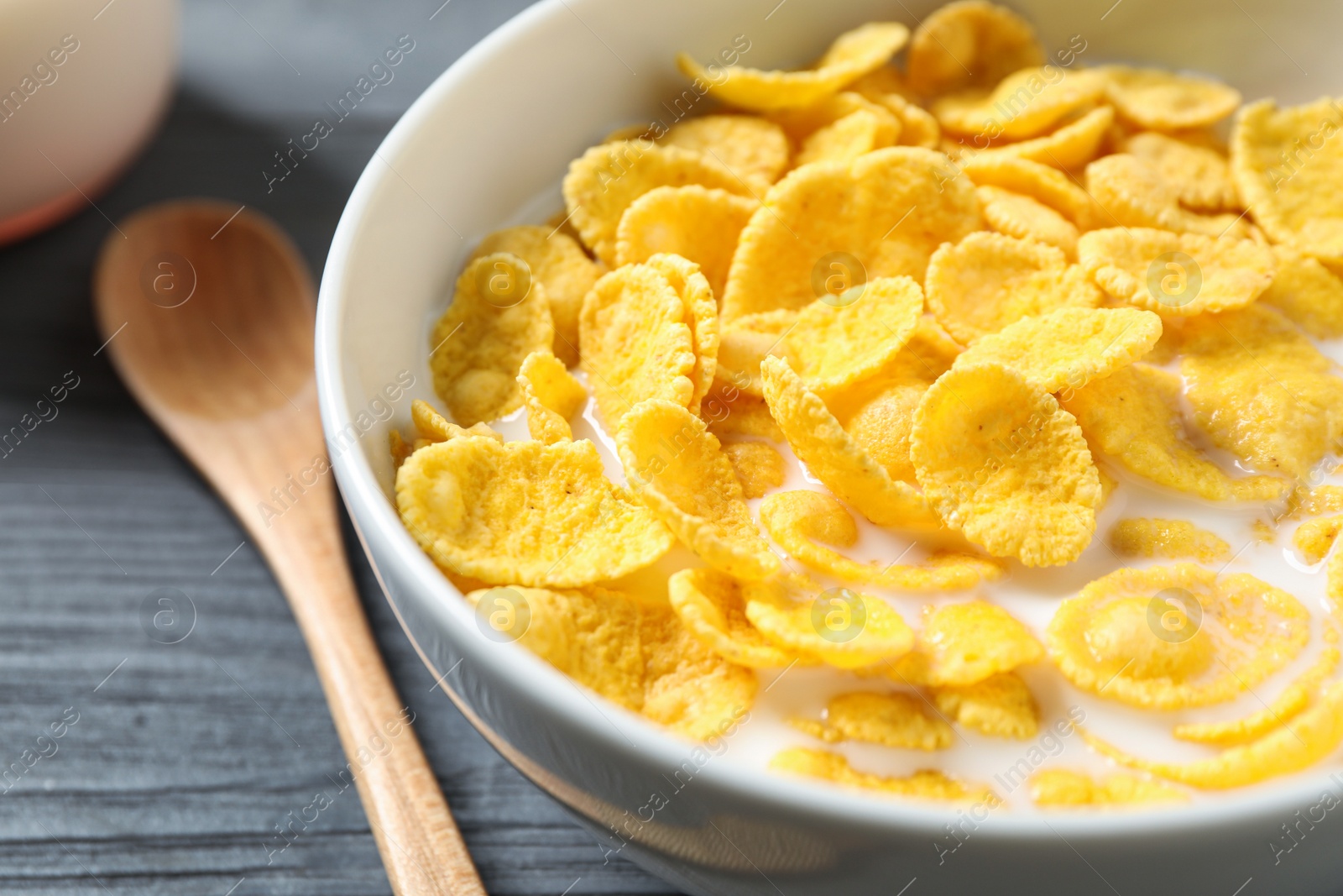 Photo of Tasty crispy corn flakes with milk in bowl, closeup