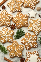 Tasty star shaped Christmas cookies with icing, spices and fir tree twigs on white marble table, flat lay