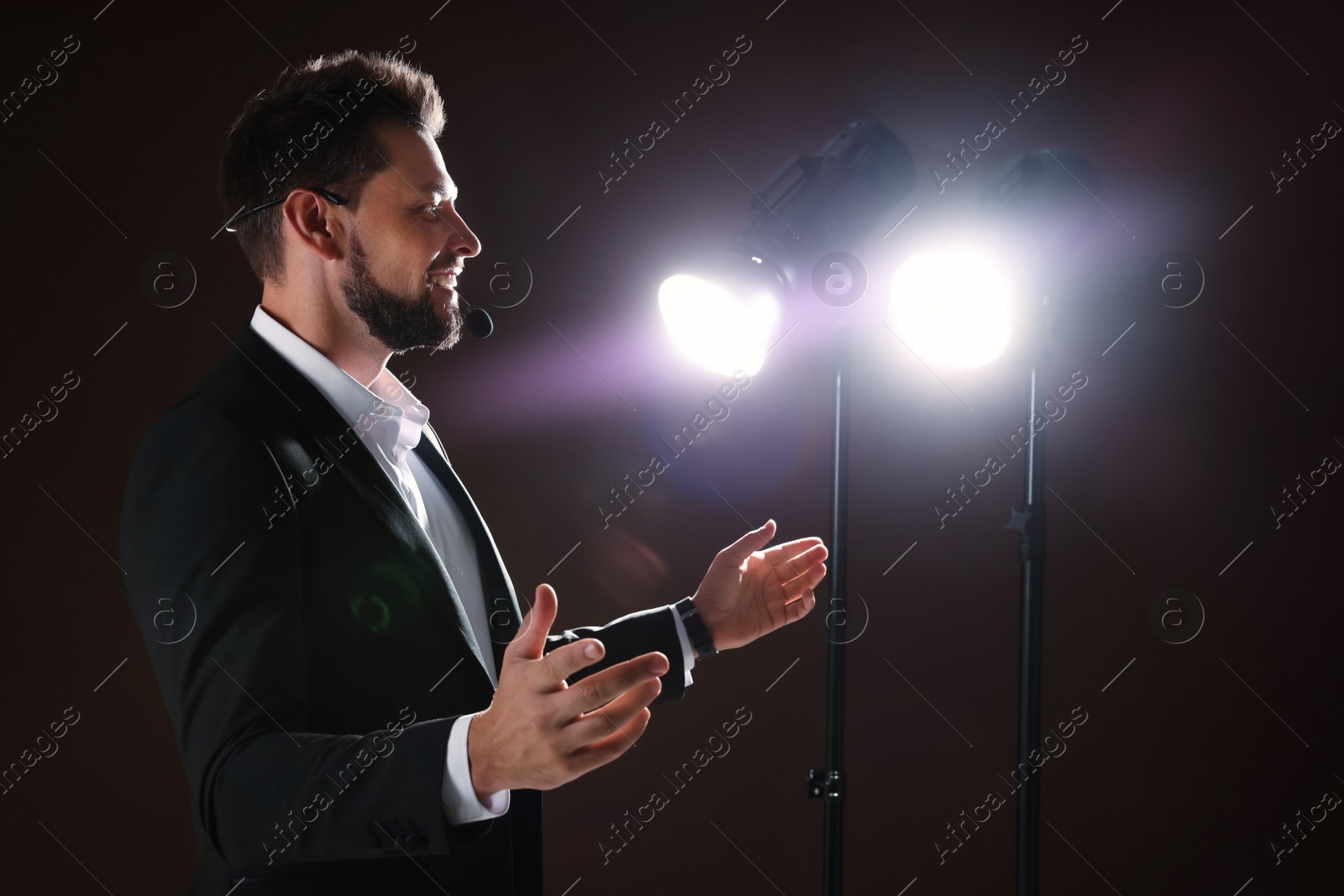 Photo of Motivational speaker with headset performing on stage. Space for text