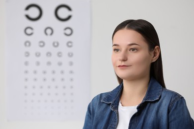 Portrait of young woman against vision test chart