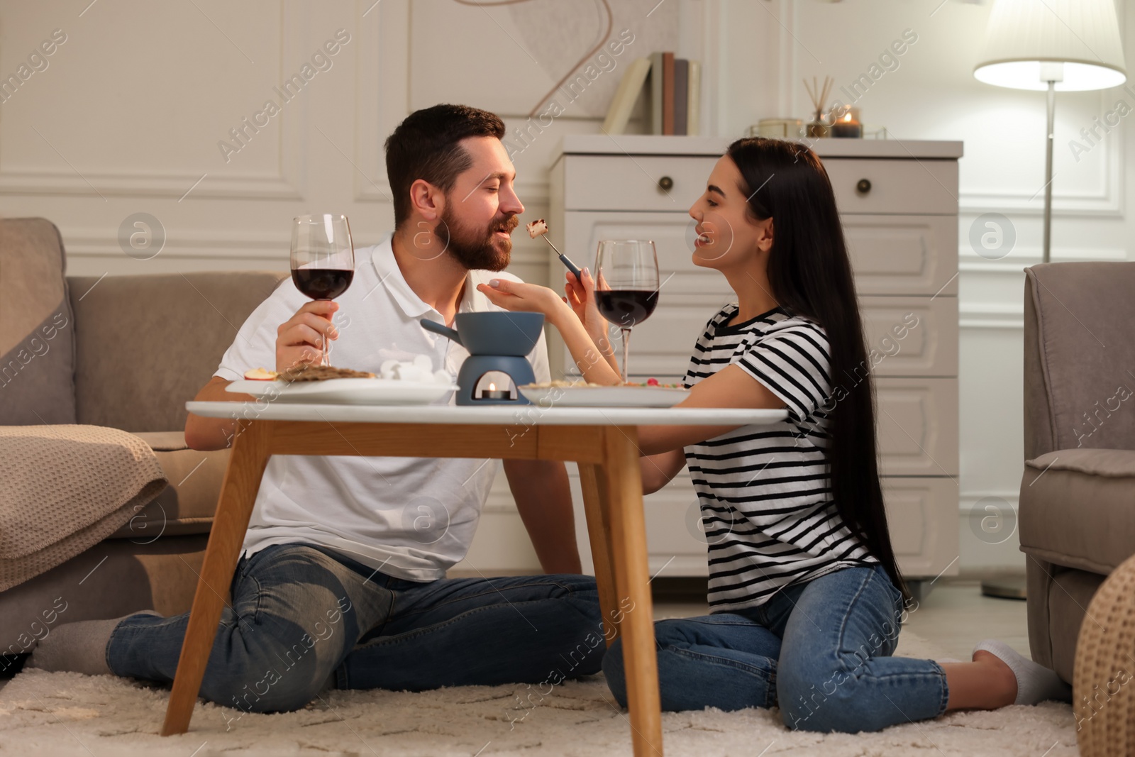 Photo of Affectionate couple enjoying chocolate fondue during romantic date at home