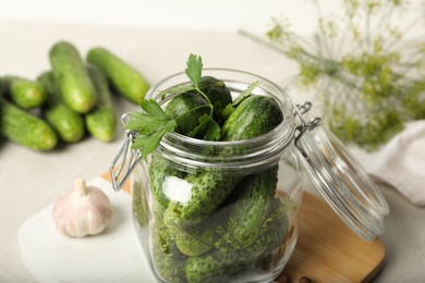 Photo of Pickling jar with fresh cucumbers on light table, closeup