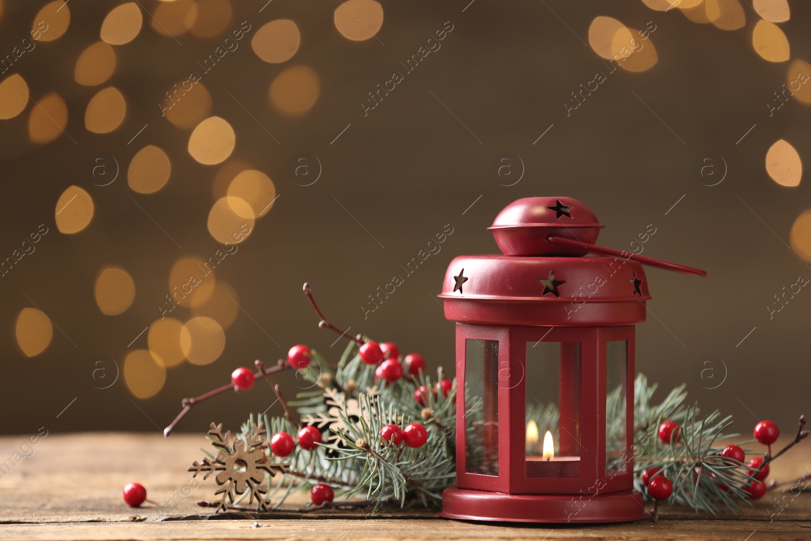 Photo of Lantern and Christmas decor on wooden table against blurred festive lights, space for text. Winter holiday