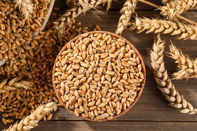 Photo of Wheat grains with spikelets on wooden table, flat lay