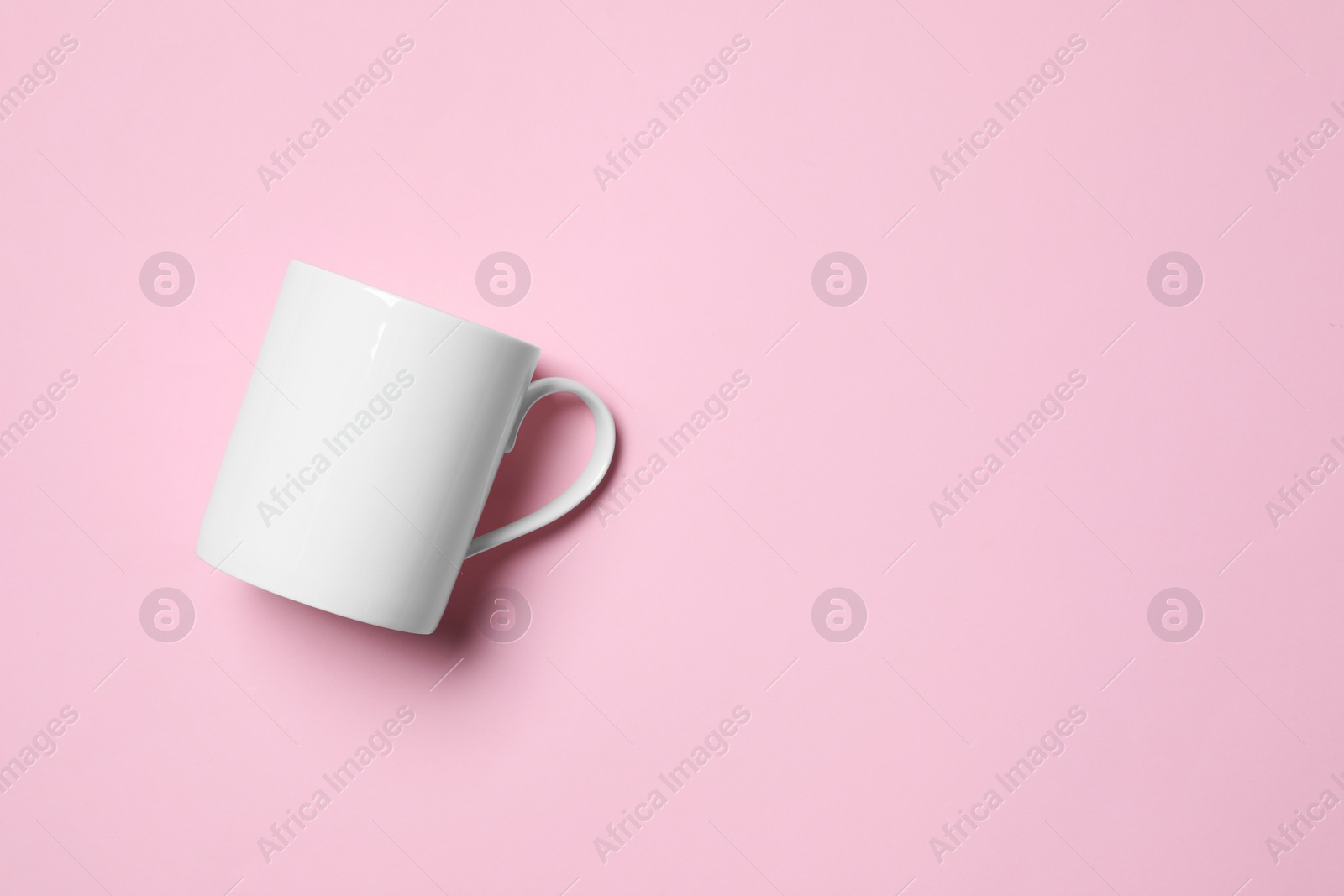 White ceramic mug on pink background, top view. Space for text Photo of White ceramic mug on pink background, top view. Space for text