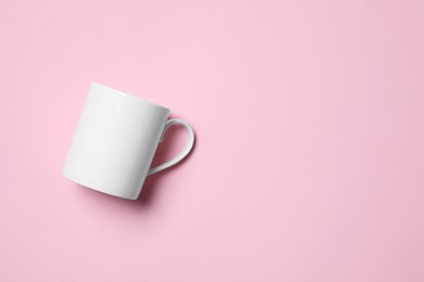Photo of White ceramic mug on pink background, top view. Space for text