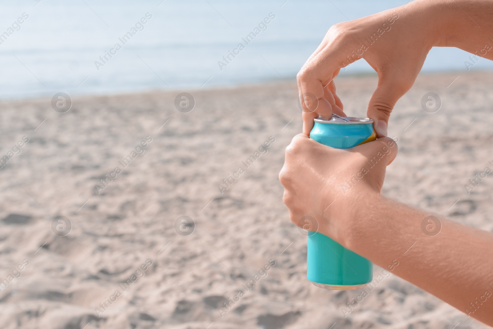 Photo of Woman opening aluminum can with beverage on beach, closeup. Space for text