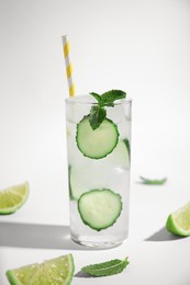 Photo of Glass of tasty fresh cucumber water with mint and sliced lime on white background