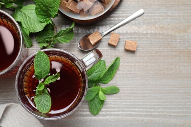 Photo of Flat lay composition with cup of hot aromatic mint tea on wooden table, space for text