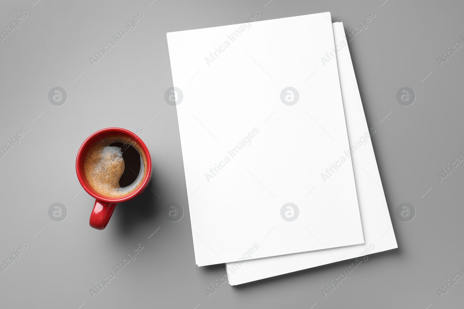 Photo of Blank paper sheets for brochure and cup of coffee on grey background, flat lay. Mock up