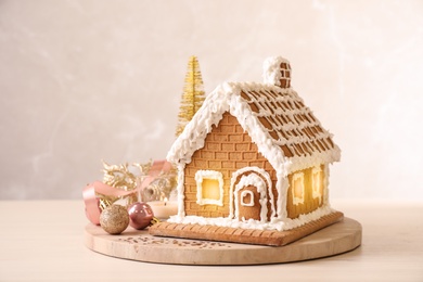 Beautiful gingerbread house decorated with icing and Christmas balls on table