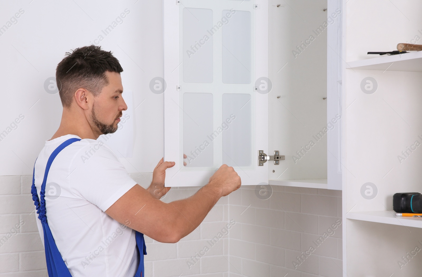 Photo of Worker installing door of cabinet in kitchen