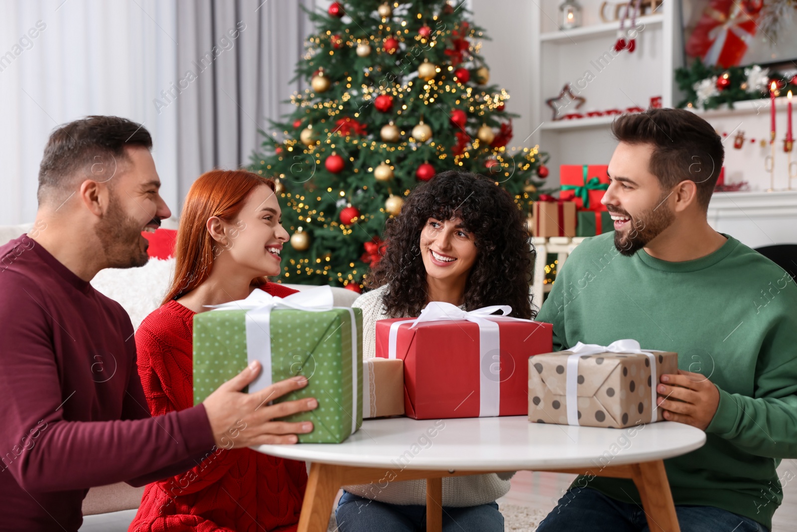 Photo of Christmas celebration. Happy friends exchanging gifts at home