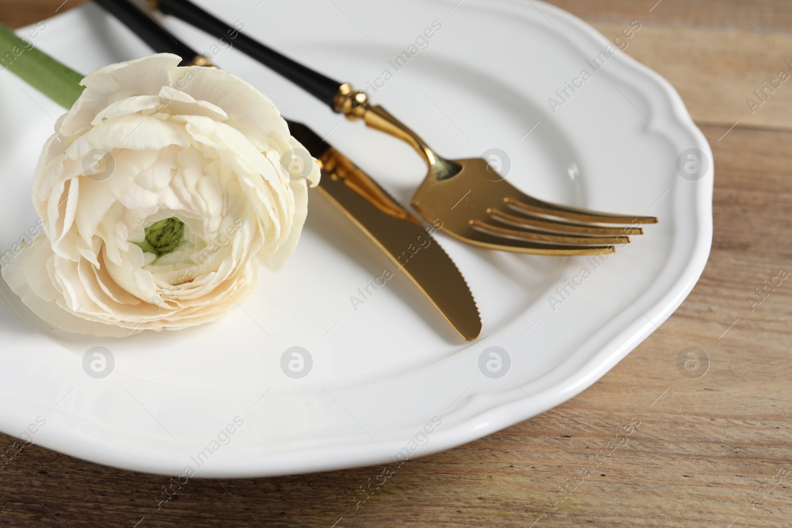 Photo of Stylish table setting with cutlery and flower on wooden background, closeup