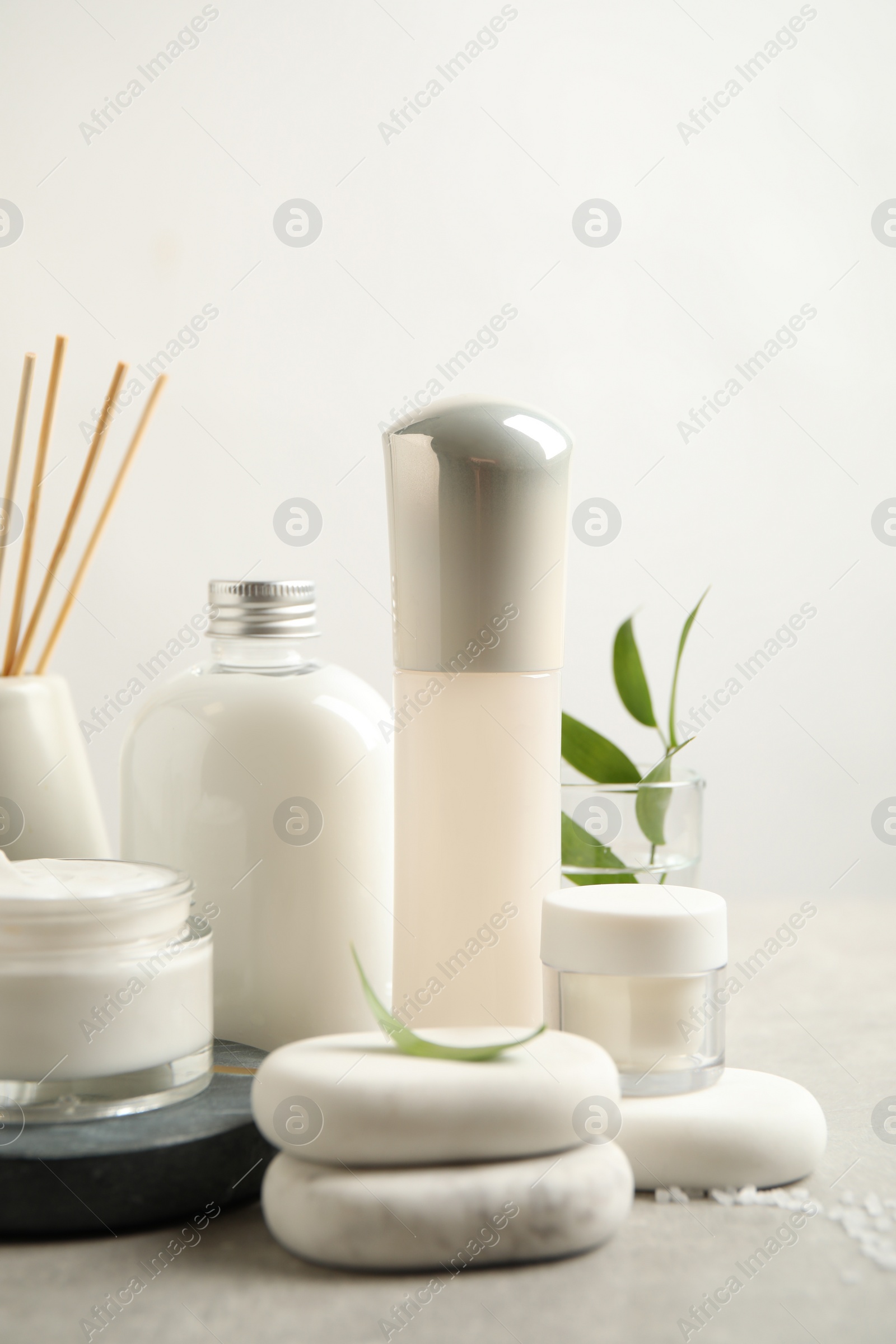 Photo of Composition with skin care products and spa stones on light background, closeup