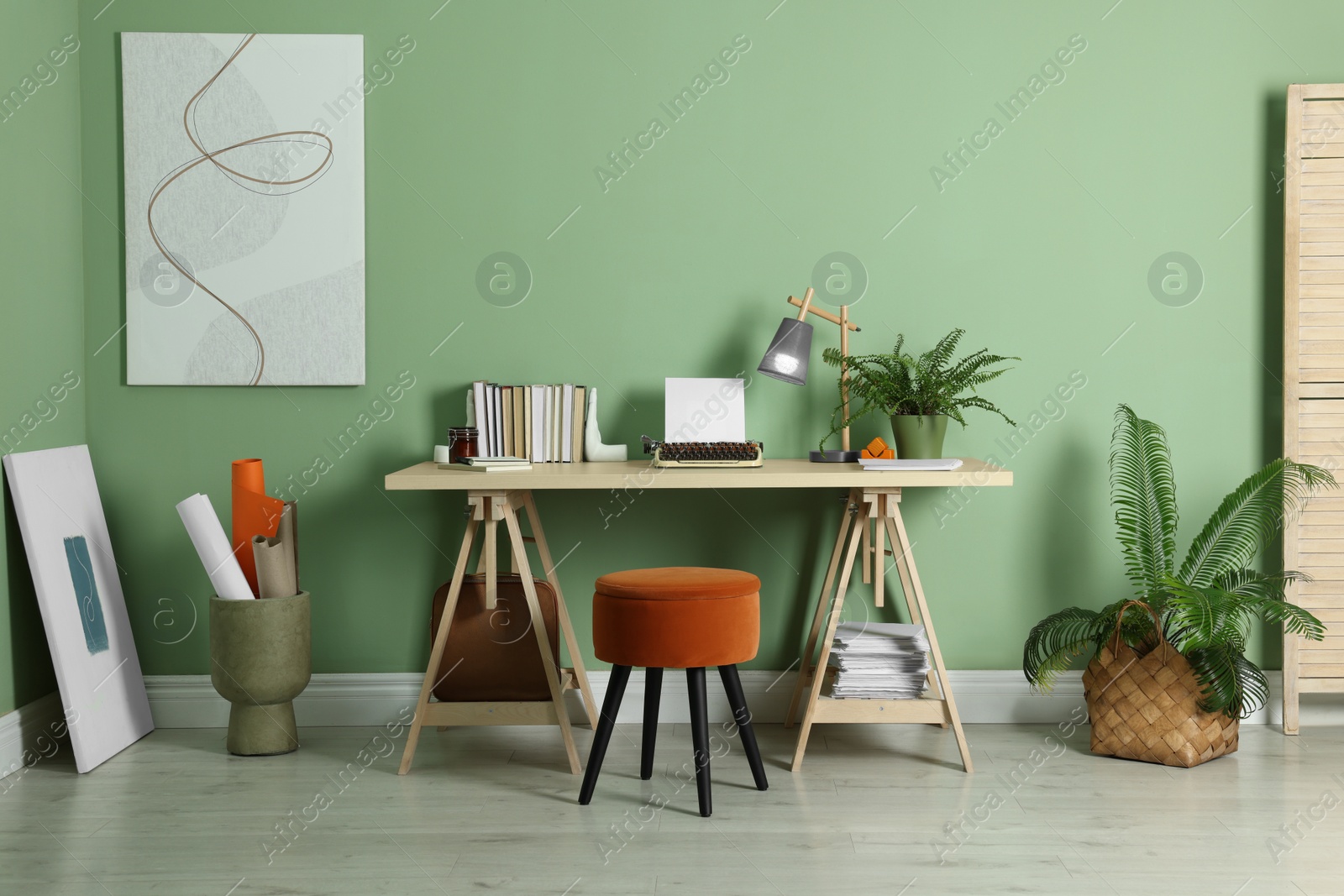 Photo of Writer's workplace with typewriter on wooden desk near pale green wall in room