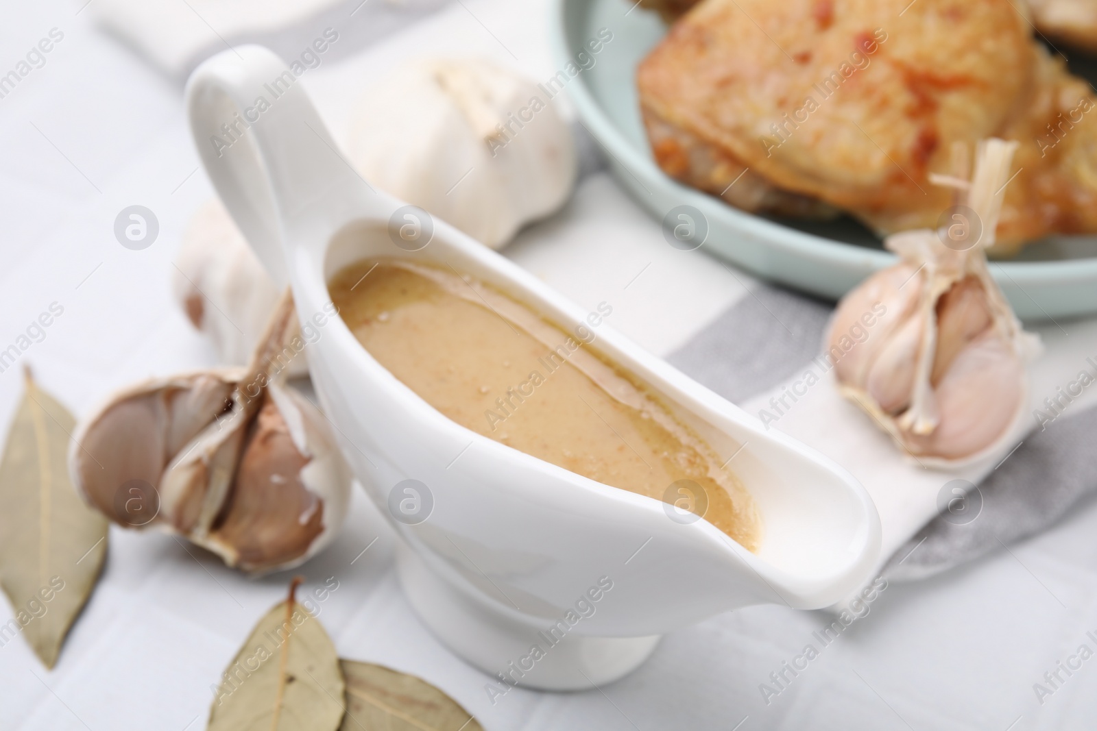 Photo of Delicious turkey gravy in sauce boat on white table, closeup