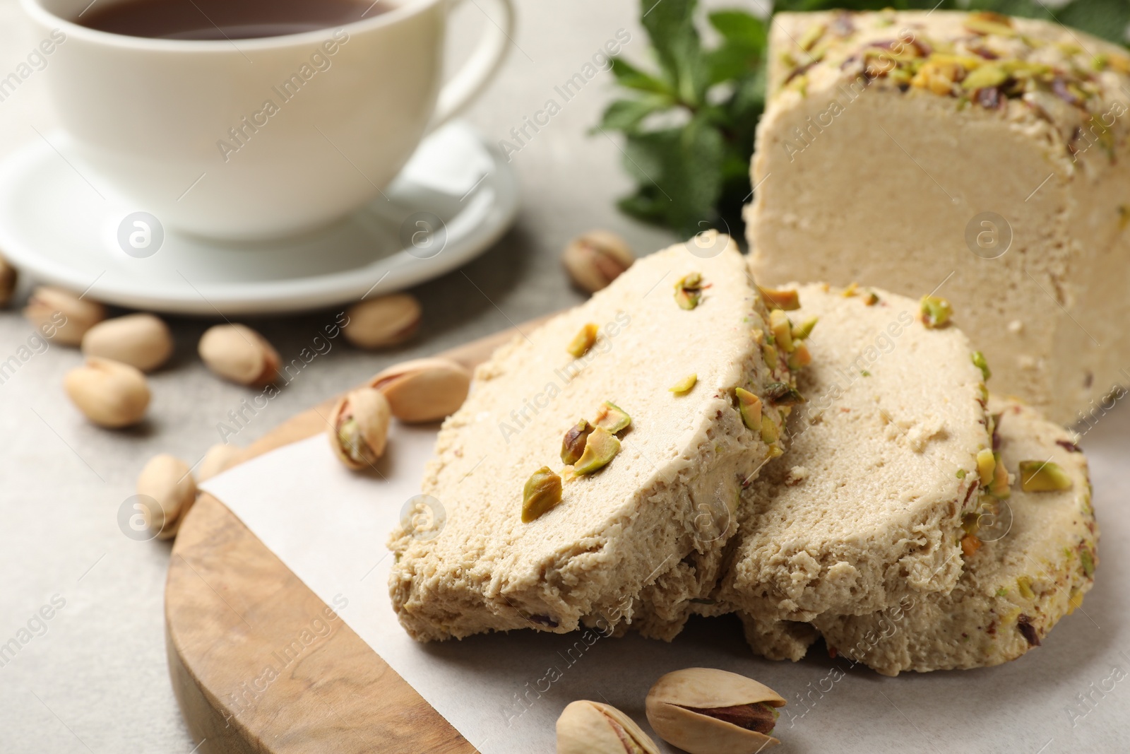 Photo of Tasty halva with pistachios served on grey table, closeup