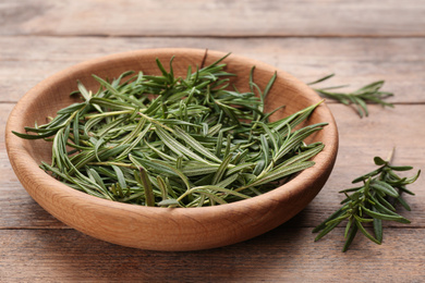 Fresh rosemary in bowl on wooden table