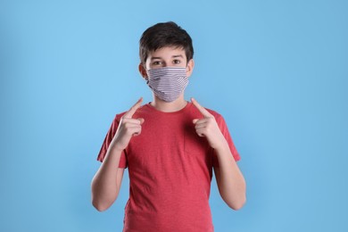 Photo of Boy wearing protective mask on light blue background. Child safety