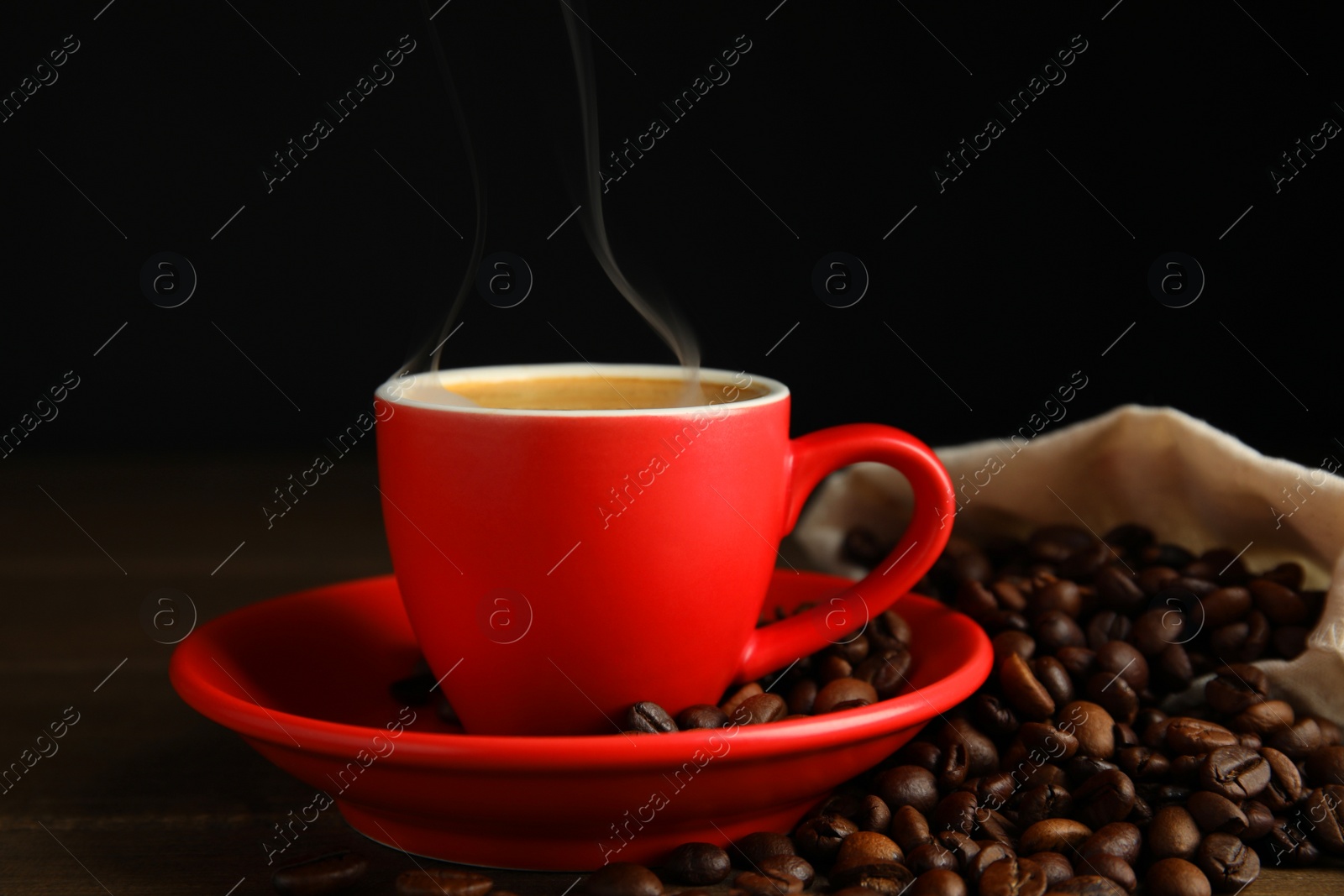 Photo of Cup of tasty coffee and beans on wooden table
