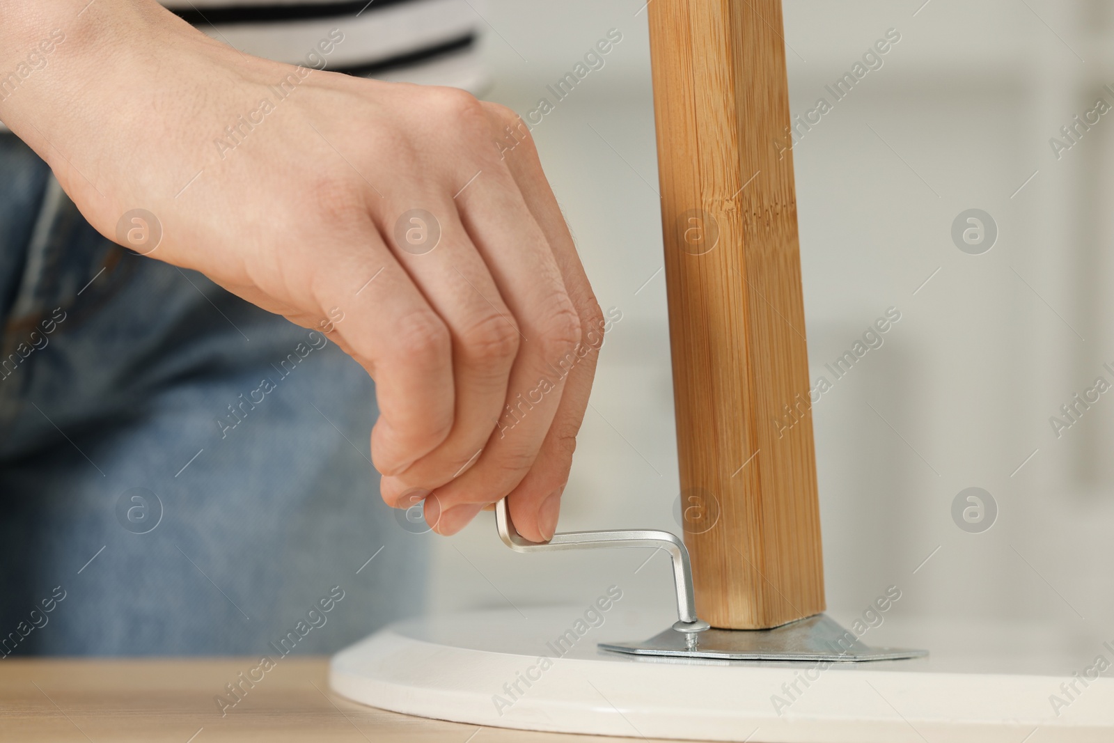 Photo of Woman with hex key assembling furniture indoors, closeup