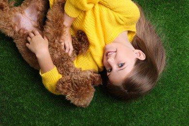 Photo of Little child with cute puppy on green grass, top view. Lovely pet