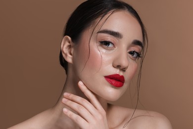 Photo of Portrait of beautiful young woman with red lips on brown background, closeup