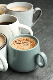 Many cups of different coffees on slate table, closeup