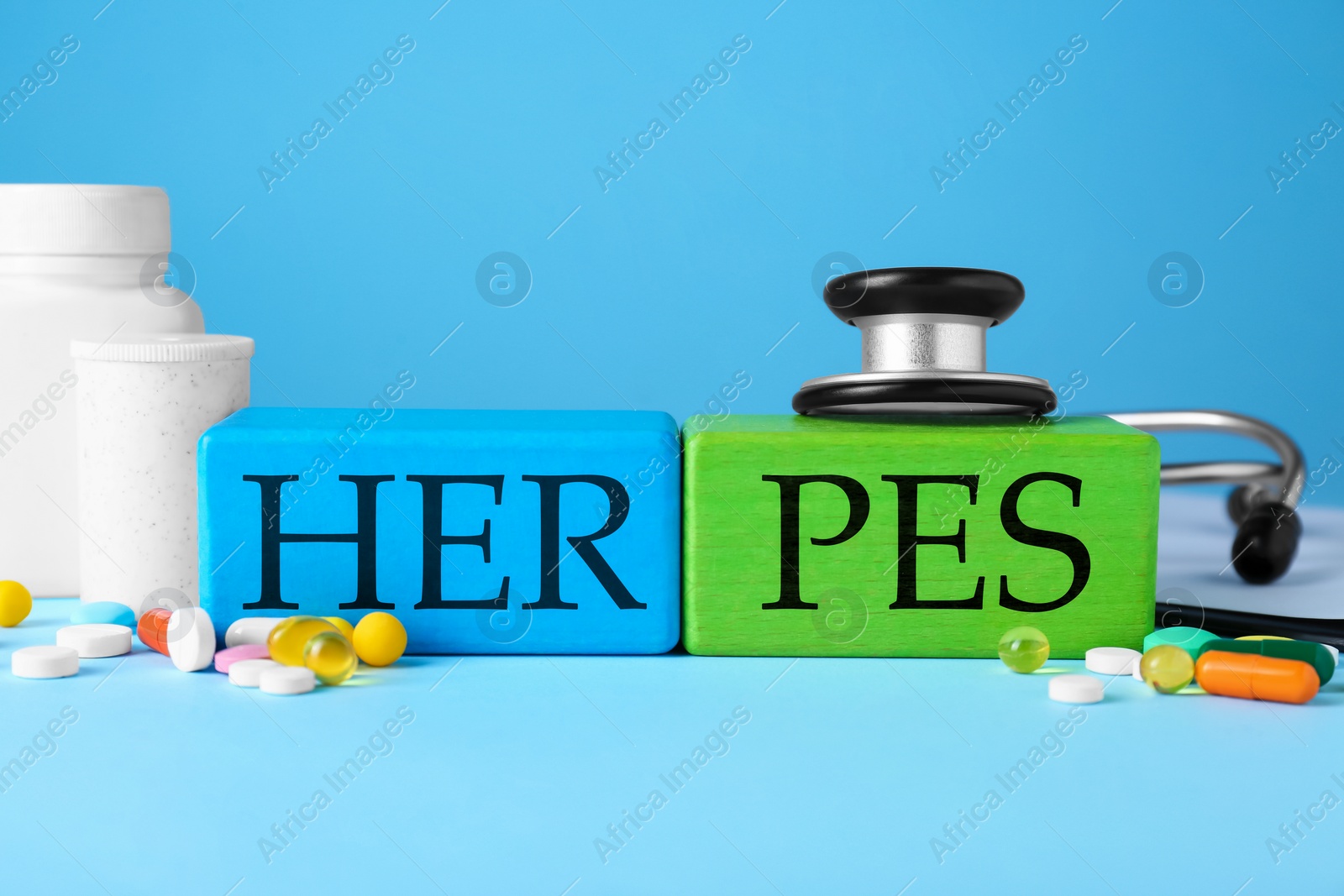 Photo of Word Herpes made of colorful cubes, different pills and stethoscope on light blue background