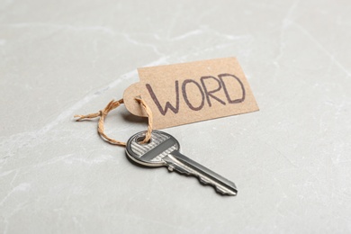 Photo of Metal key with tag on light grey table. Keyword concept