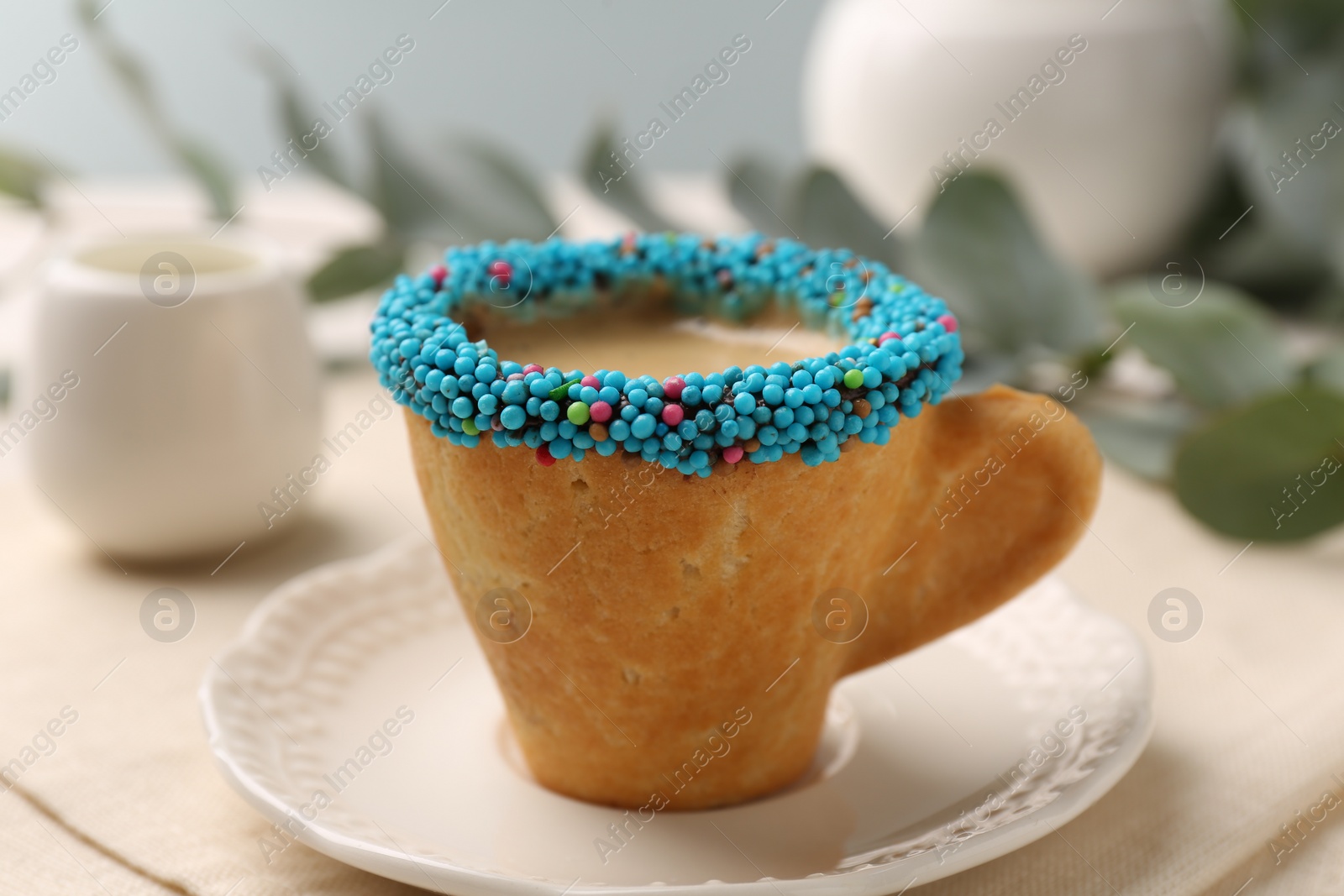 Photo of Delicious edible biscuit cup of espresso decorated with sprinkles on table, closeup