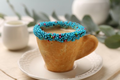 Delicious edible biscuit cup of espresso decorated with sprinkles on table, closeup