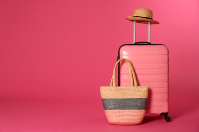 Photo of Stylish suitcase with hat and beach bag on color background. Space for text