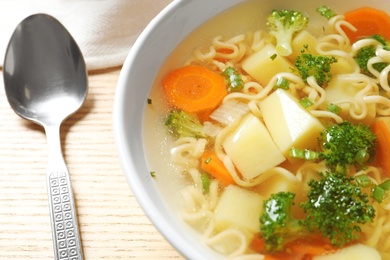 Bowl of fresh homemade vegetable soup served on wooden table, closeup