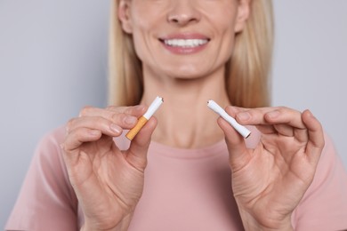 Photo of Woman with broken cigarette on light grey background, closeup. Stop smoking concept