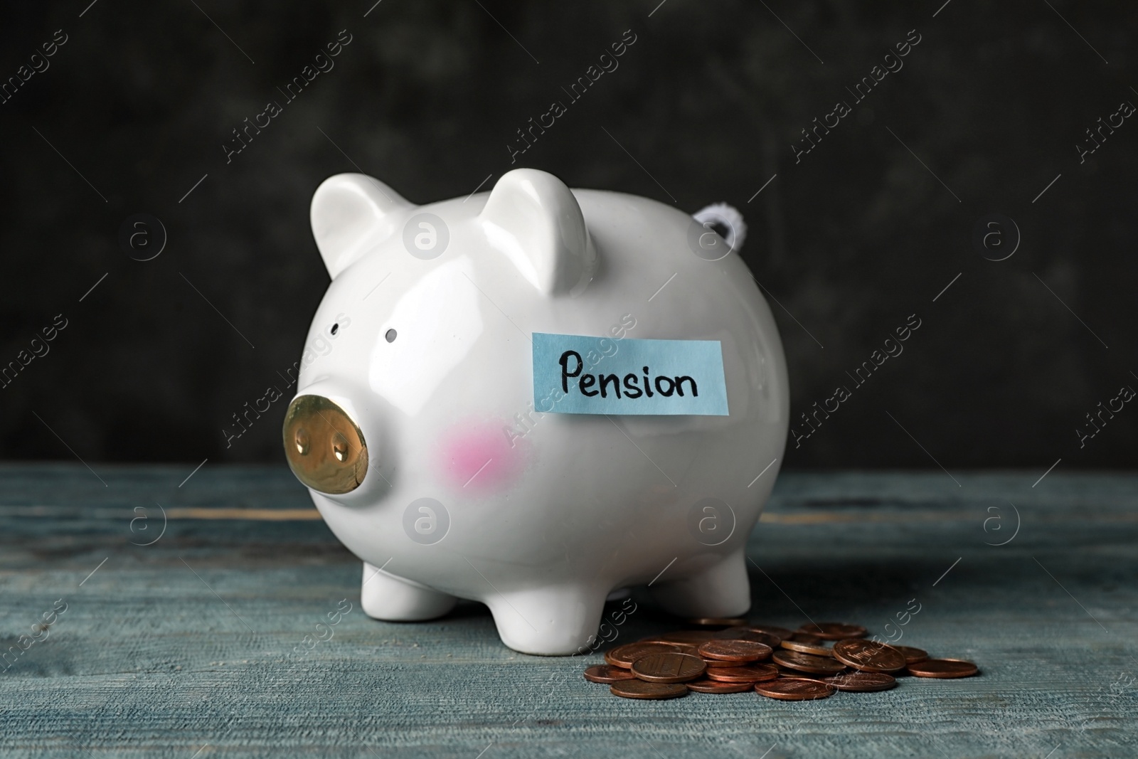 Photo of Piggy bank with word PENSION and coins on table