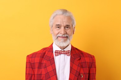 Photo of Portrait of grandpa with stylish red suit and bowtie on yellow background