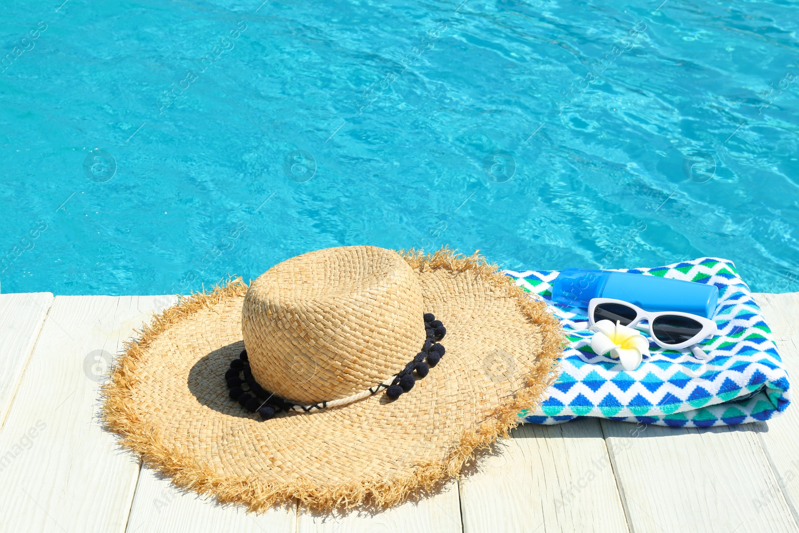 Photo of Beach accessories on wooden deck near swimming pool. Space for text