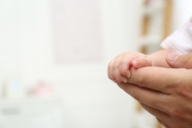 Father with his little baby at home, closeup of hands. Space for text