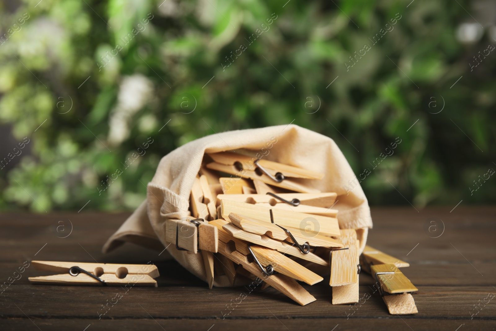 Photo of Sack bag with wooden clothespins on table against blurred green background