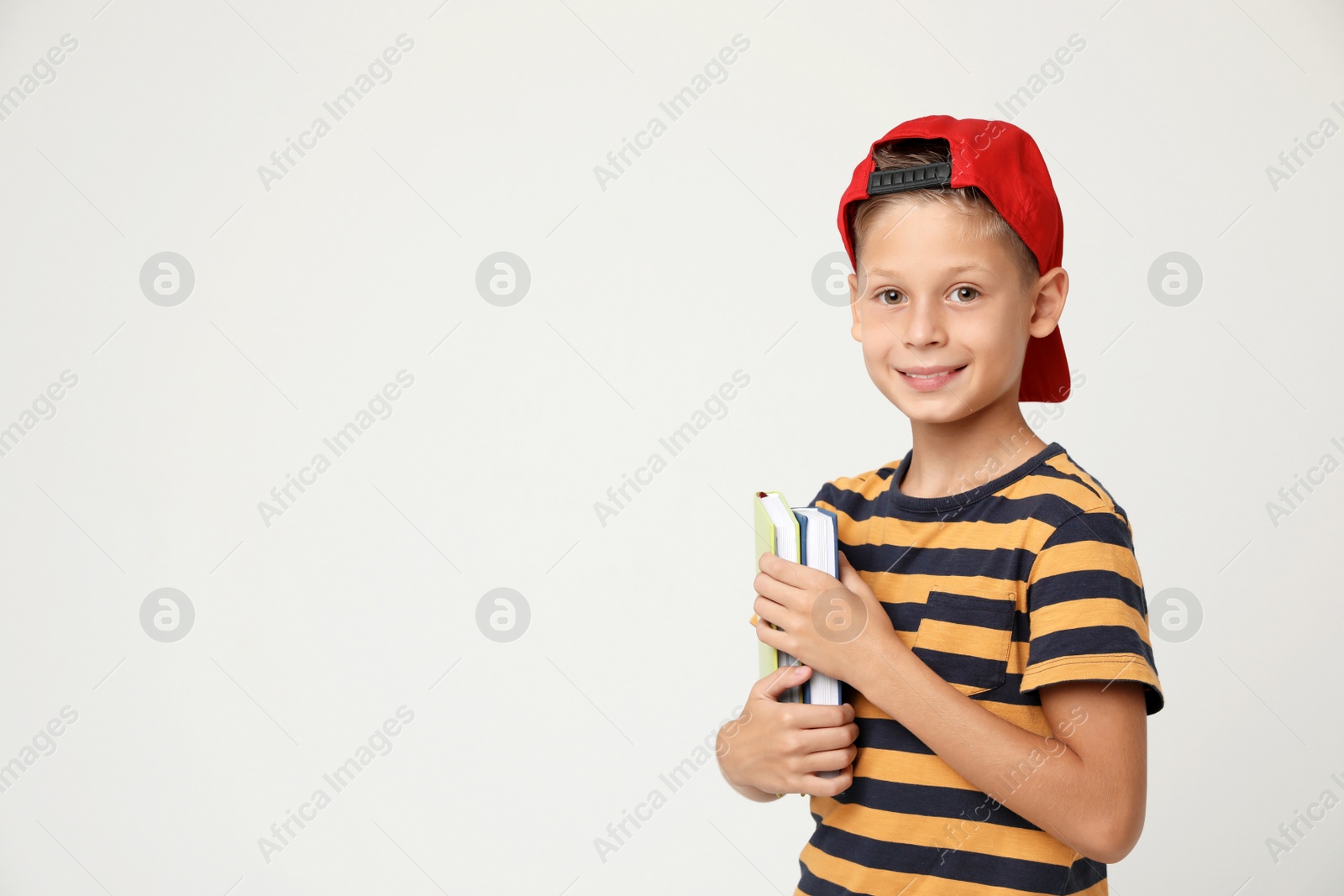 Photo of Portrait of cute little boy with books on grey background, space for text. Reading concept