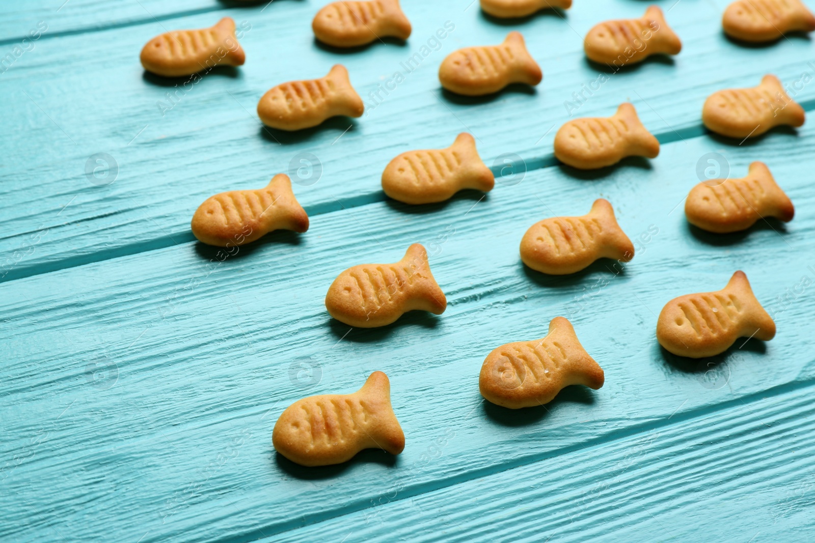 Photo of Delicious fish shaped crackers on light blue wooden table, closeup