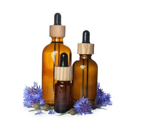 Photo of Bottles of essential oil and cornflowers on white background