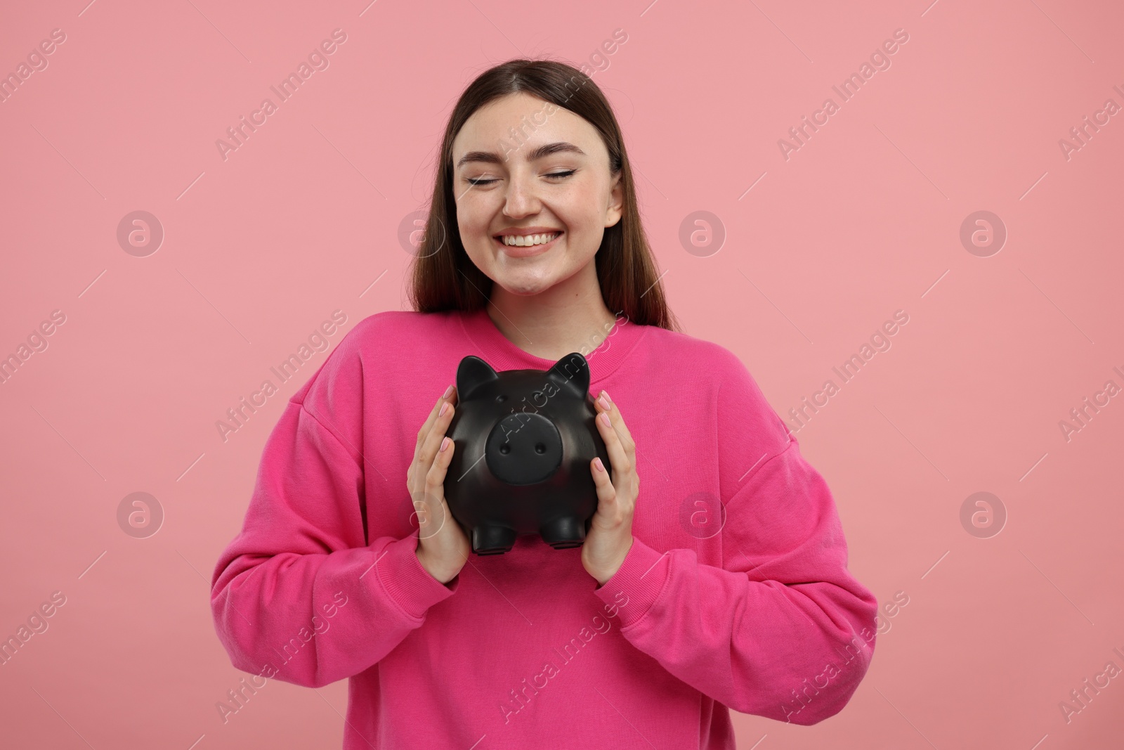 Photo of Happy woman with piggy bank on pink background