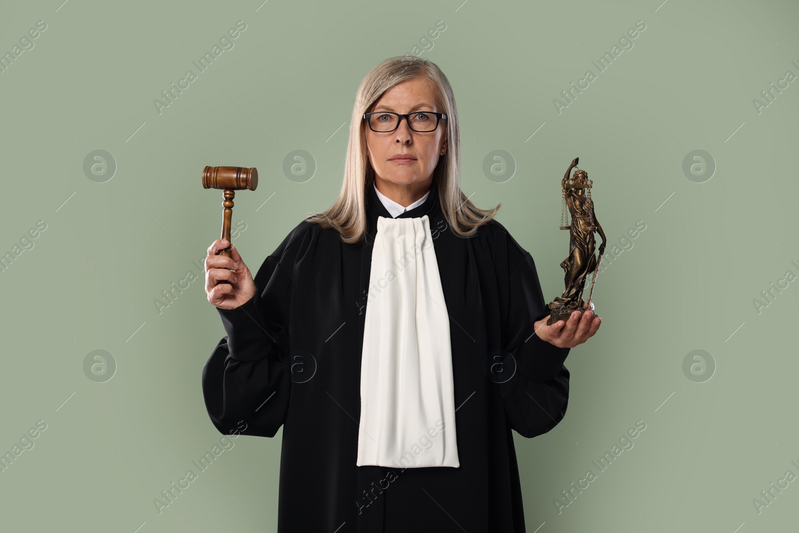 Photo of Senior judge with gavel and figure of Lady Justice on green background